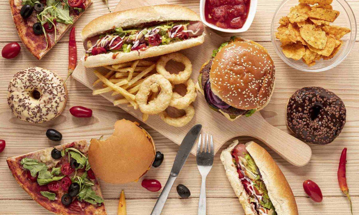 Mesa com diversos alimentos ultraprocessados: sanduíches, doces, batatas, refris molhos -  (crédito: Freepik)