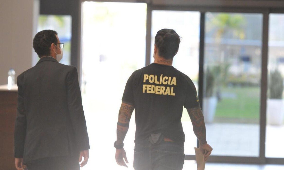 Policial federal ao lado de outro homem, no aeroporto de Confins. -  (crédito: Alexandre Guzanshe/EM/D.A Press)