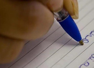 Pessoa escrevendo com caneta em papel -  (crédito: MARCOS SANTOS/USP IMAGENS)