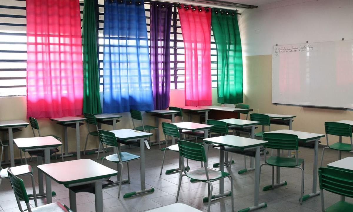 Sala de aula com carteiras vazias. Aparece parte do quadro. Ao fundo há janelas com cortinas coloridas fechadas.  -  (crédito: Rovena Rosa/Agência Brasil - Imagem meramente ilustrativa)