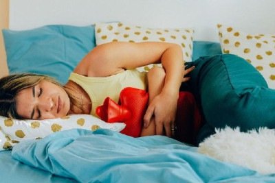 Mulher deitada, encolhida, com dor em cólica -  (crédito: Getty Images)