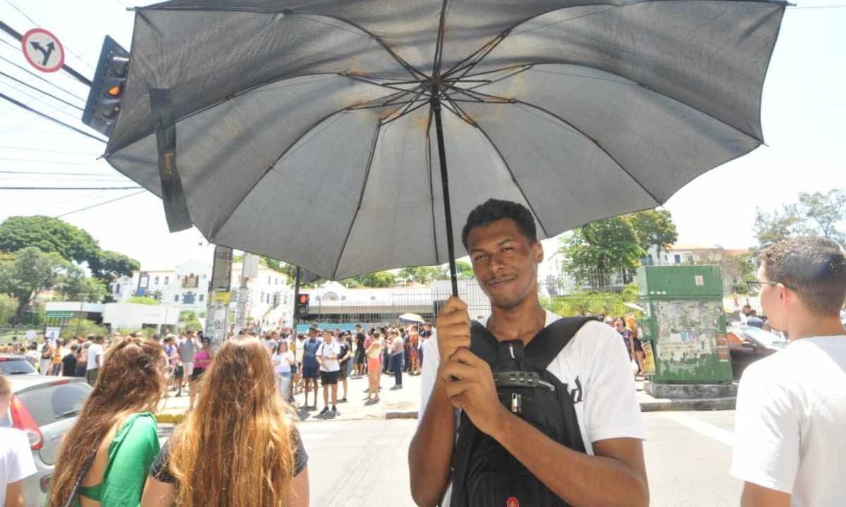 Estudante Weverton Ferreira com um guarda-chuva para se proteger do sol