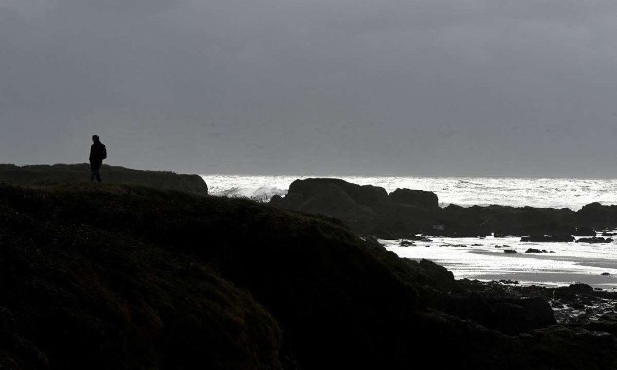 Homem caminha na praia de  Batz-sur-mer, na França
       -  (crédito:  SALOM-GOMIS / AFP       )