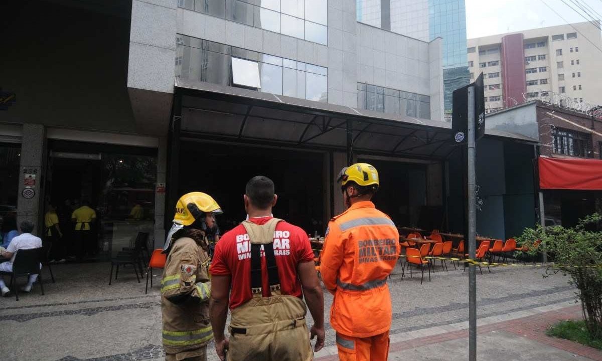 três militares do corpo de bombeiros olhando para restaurante que pegou fogo 