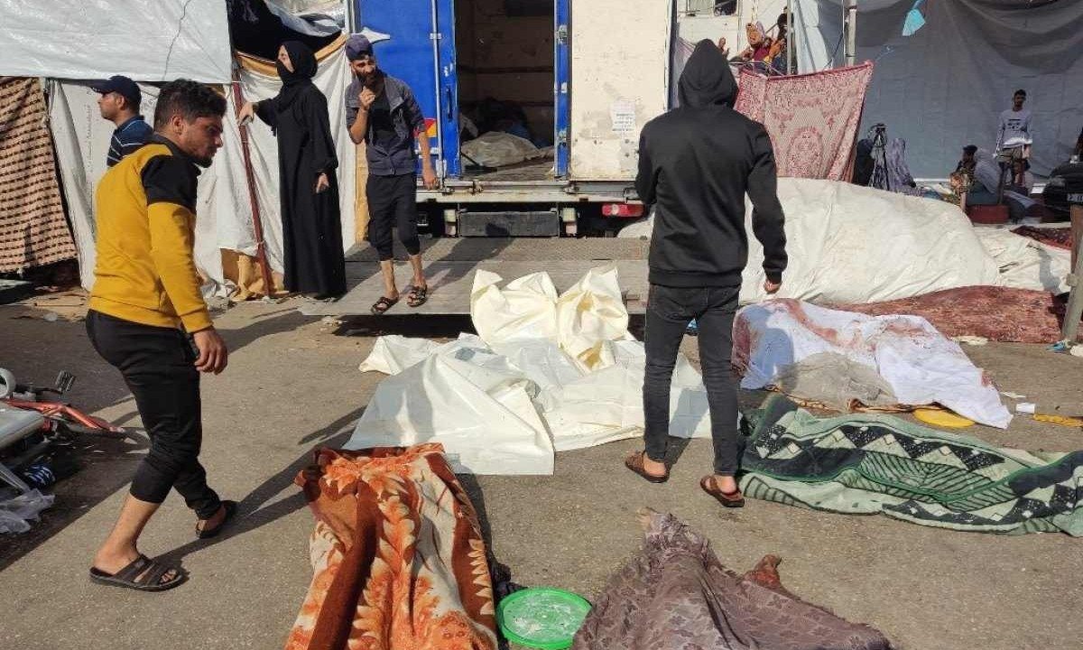 Palestinos observam corpos espalhados pelo chão, em suposto bombardeio de Israel a um hospital de Gaza
       -  (crédito: Khoder al-Zaanoun / AFP)