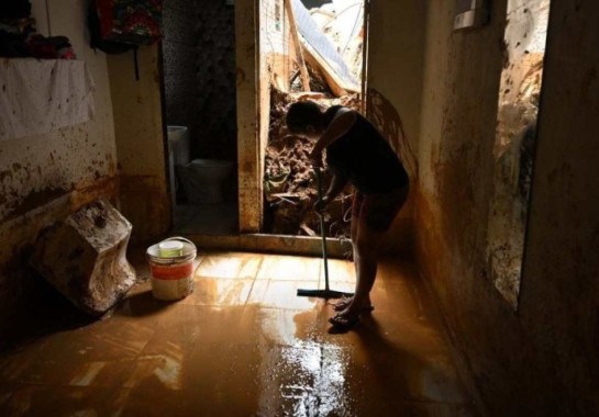 Mulher remove lama de casa afetada por enchente no bairro de Juquehy, em São Sebastião, estado de São Paulo -  (crédito: NELSON ALMEIDA / AFP)