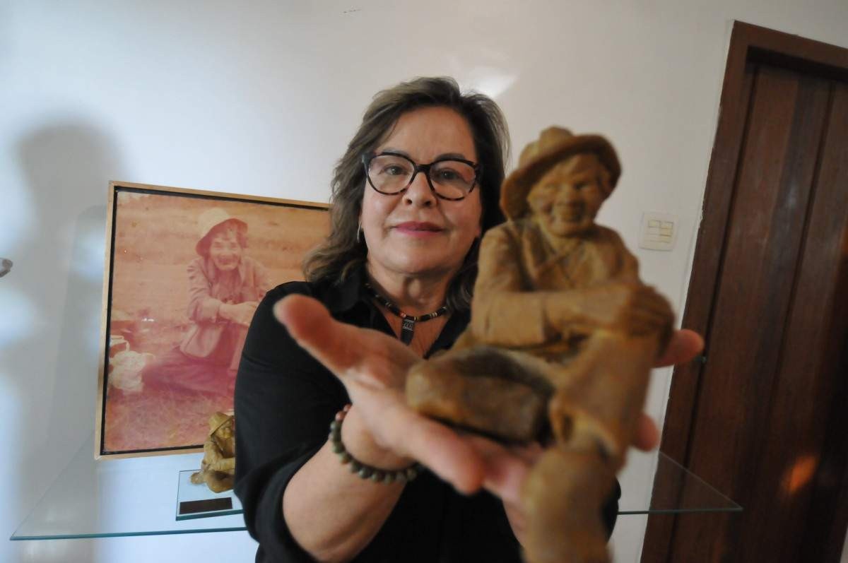 foto de uma mulher segurando uma miniatura da estátua do Juquinha da Serra do Cipó