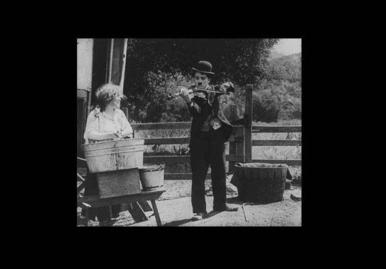 Charlie Chaplin toca violino em cena de O vagabundo, filme de 1916 -  (crédito: Reprodução)