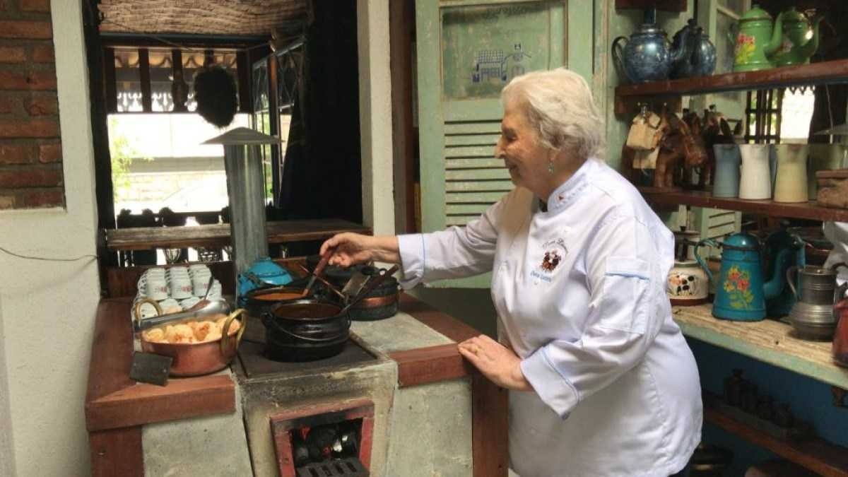 Dona Lucinha cozinhando comidas mineiras em um fogão à lenha