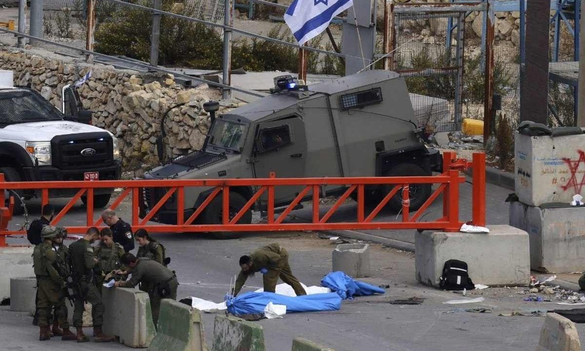 

As forças de segurança israelenses se reúnem ao lado de dois corpos cobertos em um posto de controle na entrada norte da cidade ocupada de Hebron, na Cisjordânia -  (crédito:   HAZEM BADER / AFP)