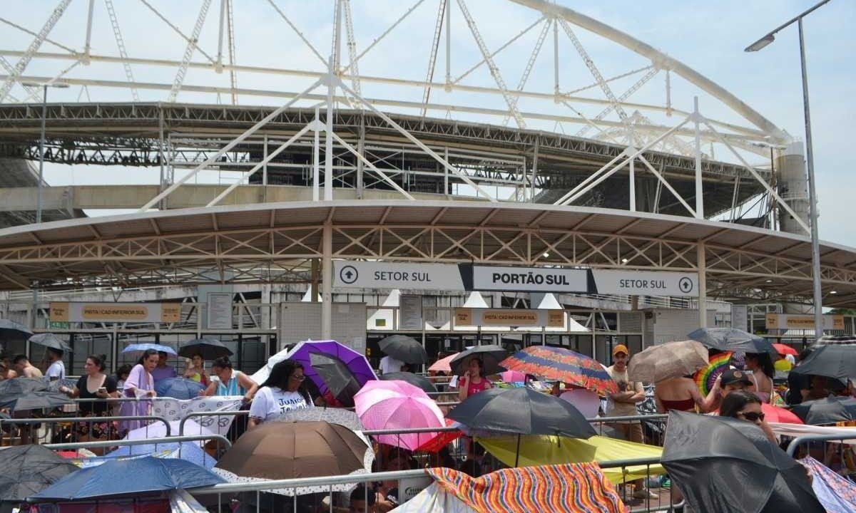  Público aglomerado do lado de fora do Estádio Nilton Santos, no RJ, usando guarda-chuvas contra o sol forte -  (crédito:  Paulo Carneiro/Ato Press/Folhapress)