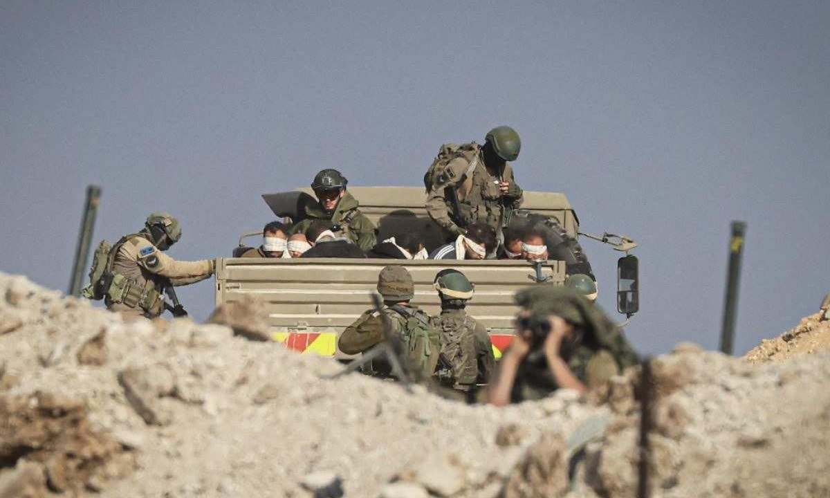  Soldados de Israel conduzem palestinos vendados em veículo militar -  (crédito: MAHMUD HAMS / AFP)