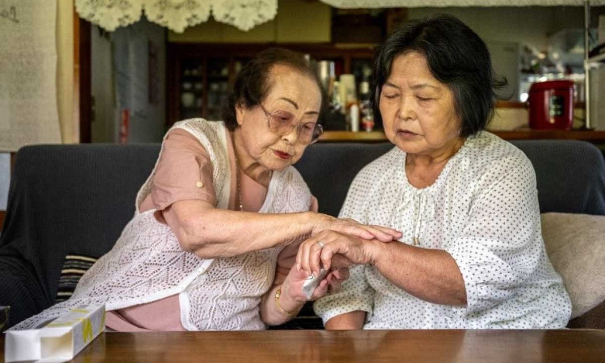 Tomoko Horino (L), 100 anos de idade, mostra produtos para uma cliente na cidade de Fukushima
       -  (crédito: Philip FONG / AFP)