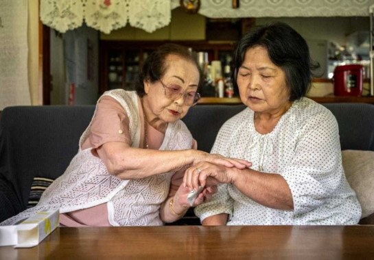 Tomoko Horino (L), 100 anos de idade, mostra produtos para uma cliente na cidade de Fukushima
       -  (crédito: Philip FONG / AFP)