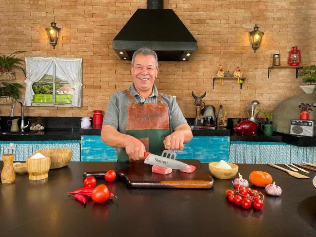  churrasqueiro e apresentador José Almiro de frente a uma mesa pronto para fazer um corte de carne