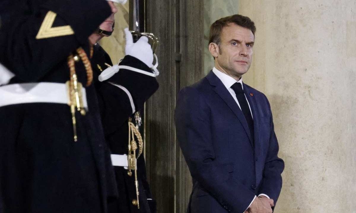  Macron, de pé, protegido por policial, no Palácio Eliseu -  (crédito: Ludovic MARIN / AFP)
