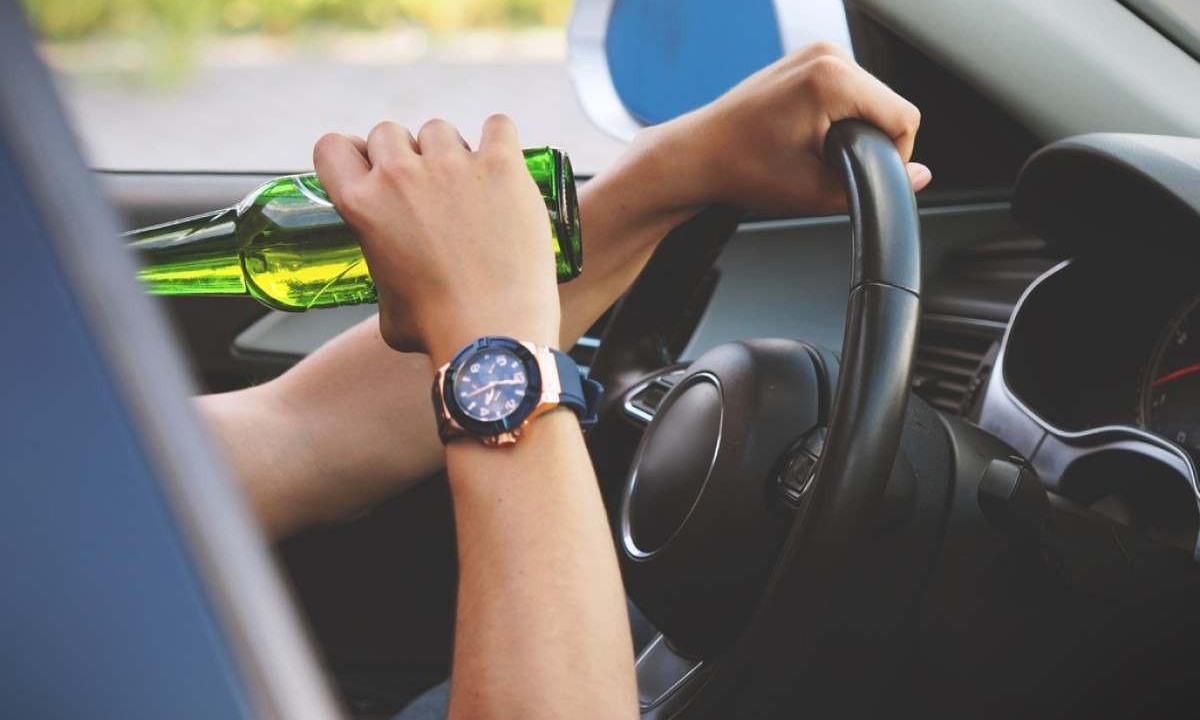 Mão de homem dirige veículo e a outra segura garrafa de cerveja -  (crédito: PxHere)
