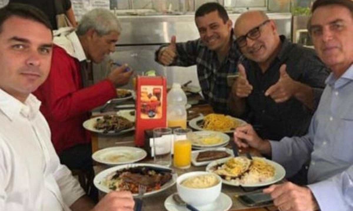 Flávio Bolsonaro (esq), Queiroz (ao centro, fazendo 'arminha') e Jair Bolsonaro (à dir) -  (crédito: Reprodução/Redes sociais)