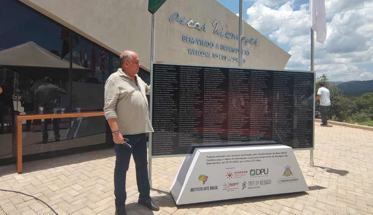 Neto Kadu Niemayer próximo da placa dos nomes das vítimas