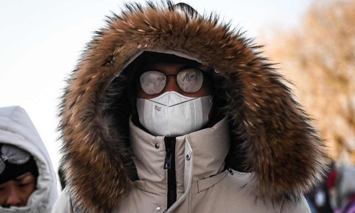Chinês usa casaco pesado contra o frio mas óculos ficam embaçados no clima enevoado 
       -  (crédito: JADE GAO / AFP)