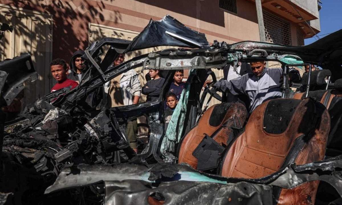  Pessoas verificam o carro em que dois jornalistas, Mustafa Thuria e Hamza Wael Dahdouh, foram mortos em um suposto ataque israelense em Rafah, na Faixa de Gaza -  (crédito:  AFP)
