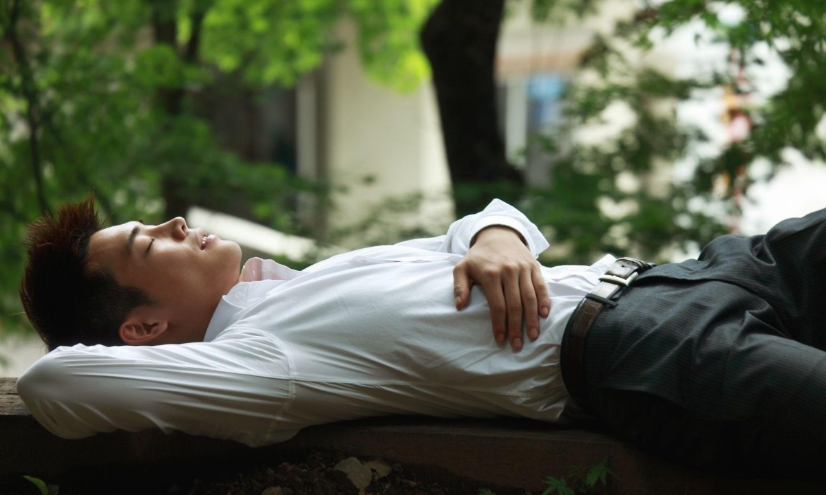 Trabalhadores japoneses cochilam em bancos de parque. É o hábito conhecido como 'hirune', ou 'soneca da tarde' -  (crédito: Getty Images)