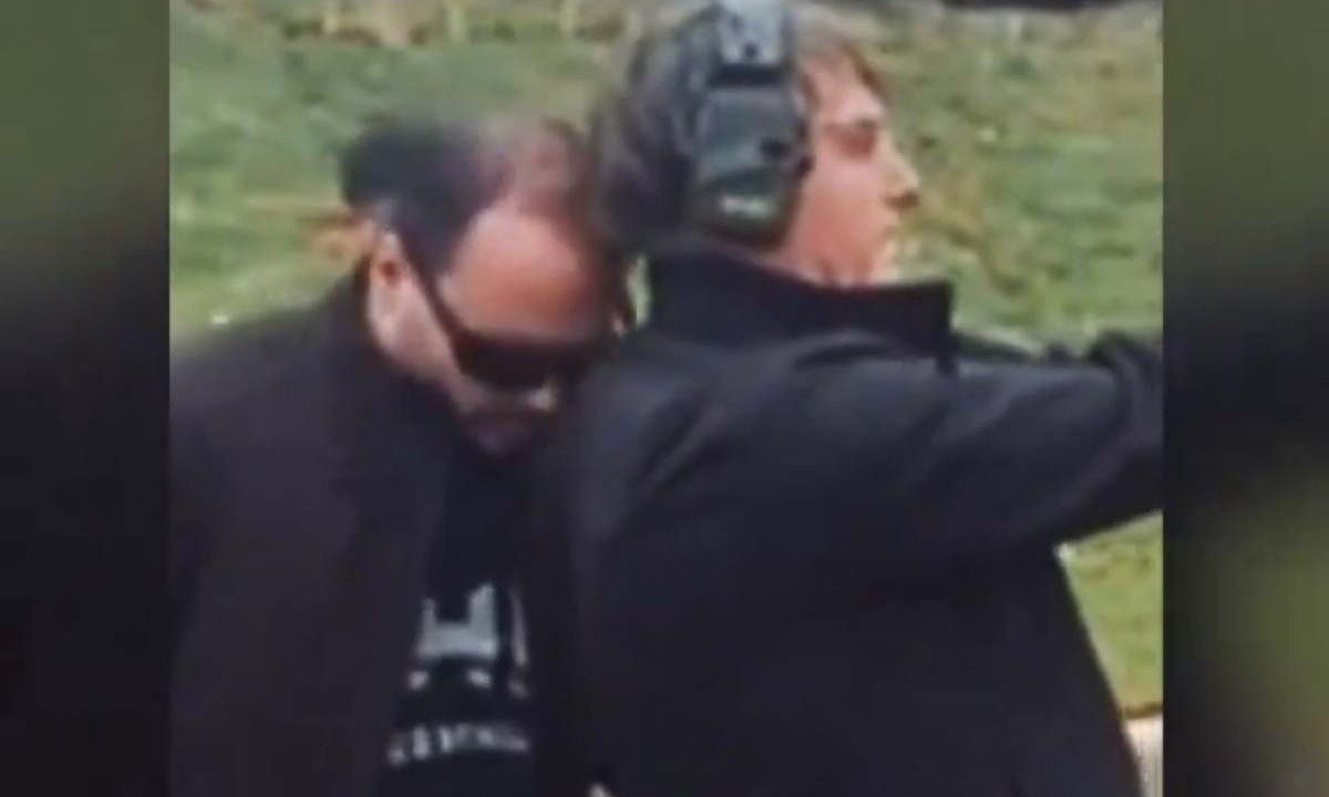 Em uma das sequ&ecirc;ncias, Carlos Bolsonaro encosta carinhosamente a cabe&ccedil;a no ombro de Jair Bolsonaro enquanto este pratica tiro em um estande -  (crédito: Reprodu&ccedil;&atilde;o/Redes Sociais)