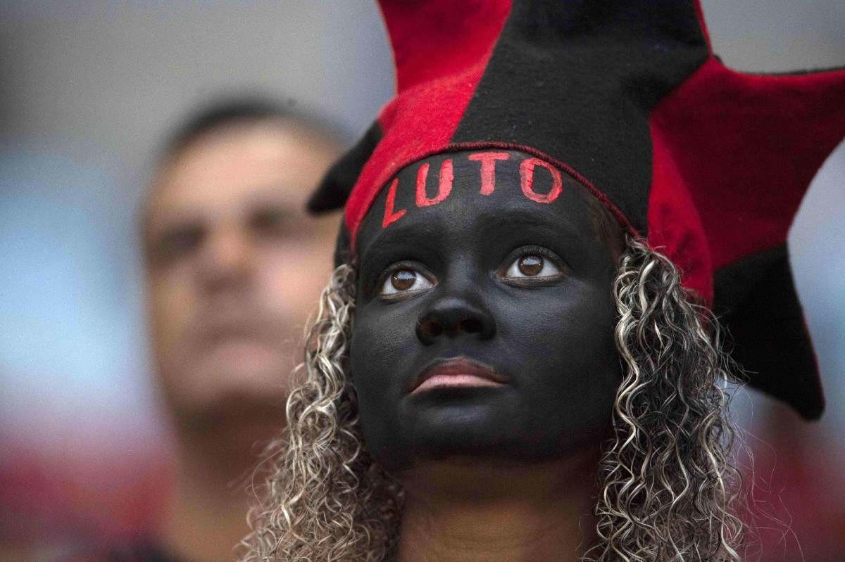 Torcedora do Flamengo com o rosto pintado de preto, com a palavra luto escrita em vermelho