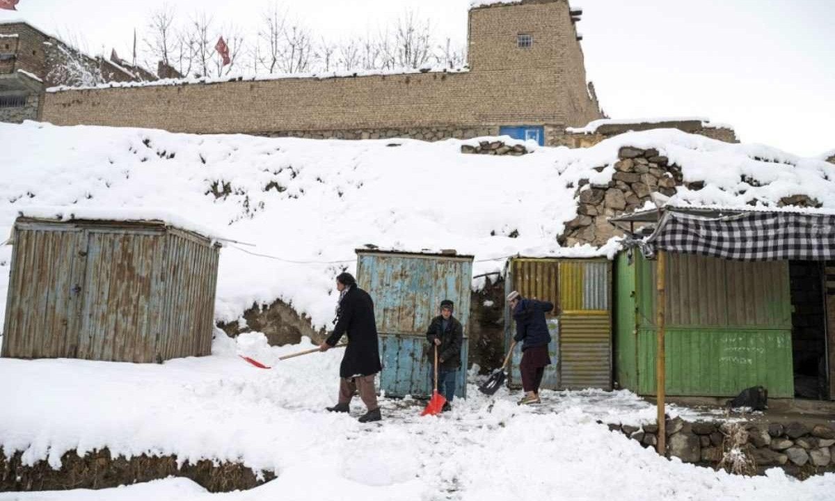  Vendedores afegãos removem neve do lado de fora de uma loja após nevar no distrito de Paghman, nos arredores de Cabul
       -  (crédito: Wakil KOHSAR / AFP)