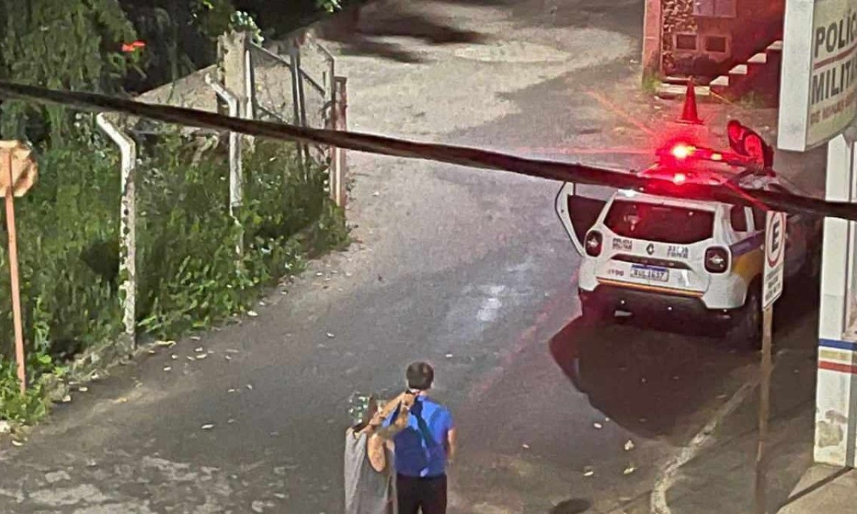 Imagem de câmera de segurança mostra o rapaz fazendo o prefeito refém em frente ao quartel, onde um policial atrás de uma viatura negocia a sua rendição -  (crédito: Divulgação/PMMG)