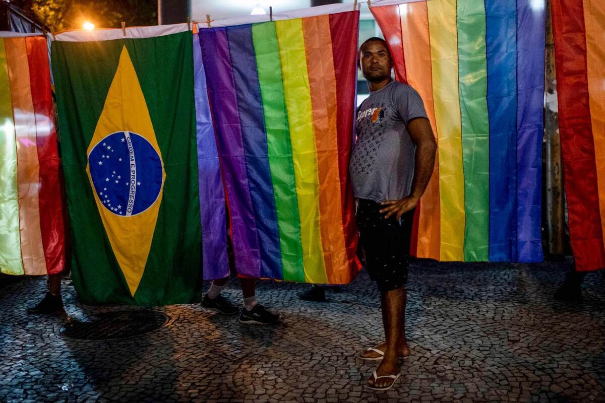 Homem vende bandeiras LGBT+ e do Brasil durante protesto contra reforma previdenciária proposta pelo então presidente Jair Bolsonaro em 2023 -  (crédito:  MAURO PIMENTEL / AFP)