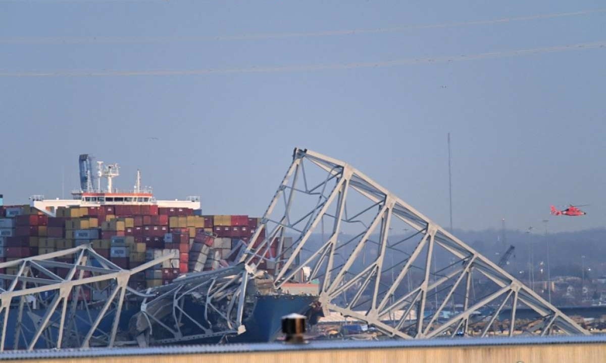 Parte da estrutura da ponte ficou sobre o navio na batida em Baltimore (EUA) -  (crédito: ROBERTO SCHMIDT / AFP)