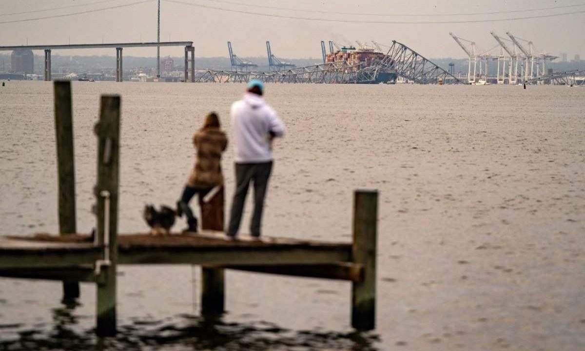  Pessoas observam navio batido e ponte que desabou -  (crédito: Kent Nishimura / AFP)