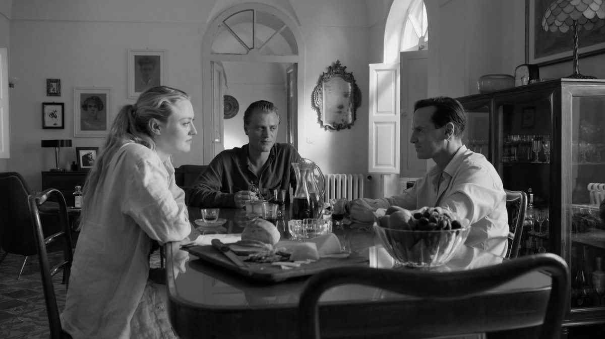 Atores Dakota Flanning, Johnny Flynn e Andrew Scott sentados à mesa em cena da série Ripley