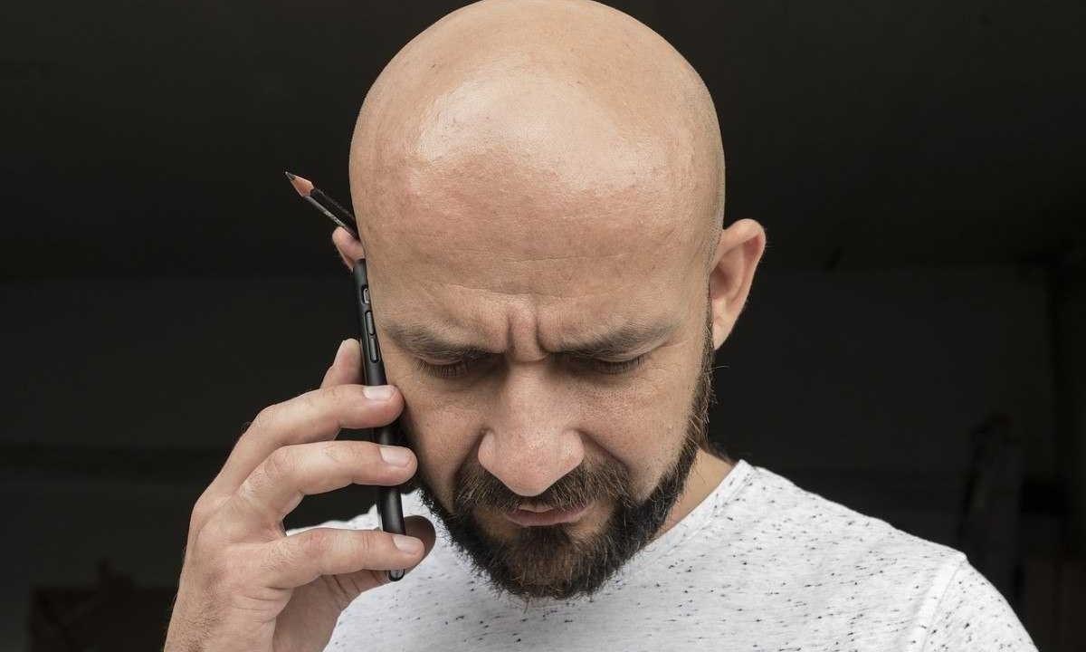 Homem careca com lápis na orelha fala ao celular; imagem meramente ilustrativa -  (crédito: Pixabay)