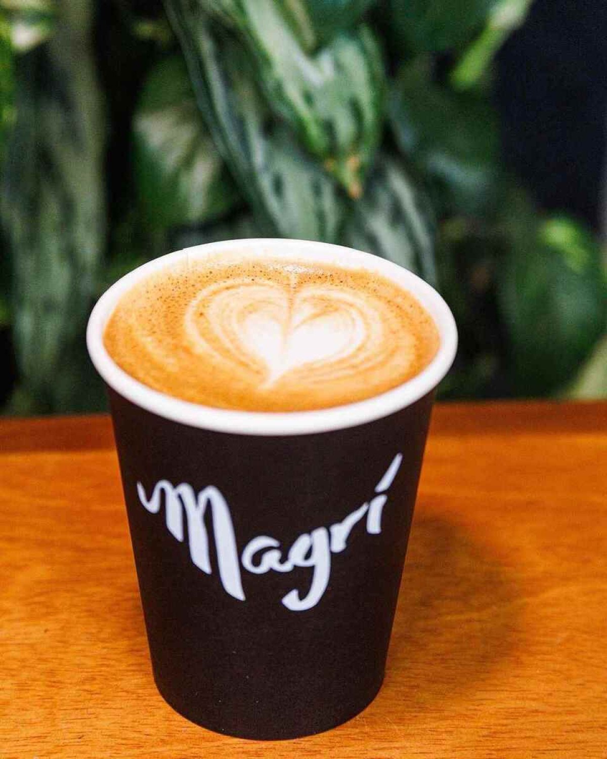 Café, com arte de leite em formato de coração em copo de papel do Magrí