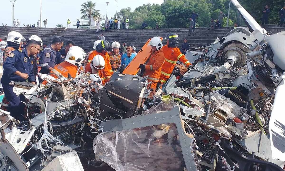 Esta foto tirada e divulgada em 23 de abril de 2024 pelo Departamento de Bombeiros e Resgate de Perak mostra equipes de resgate inspecionando o local do acidente depois que dois helicópteros militares colidiram em Lumut, no estado de Perak, na Malásia       -  (crédito: HANDOUT / PERAK'S FIRE AND RESCUE DEPARTMENT / AFP)