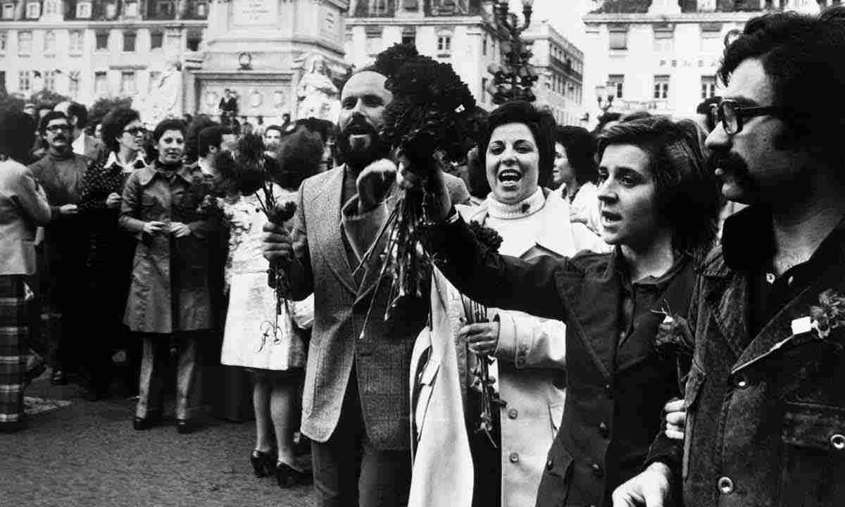 multidão segura buquês de cravos, na praça do Rossio, em Lisboa, em comemoração ao fim do regime ditatorial, que vigorou em Portugal por mais de 40 anos
