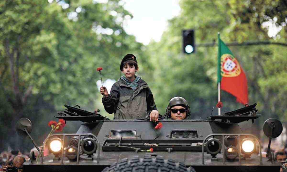 criança segurando um cravo vermelho e um ex-militar DESFILAram em  um Chaimite naS COMEMORAÇÕES DOS 50 ANOS DA REVOLUÇÃO -  (crédito: PATRICIA DE MELO MOREIRA / AFP)