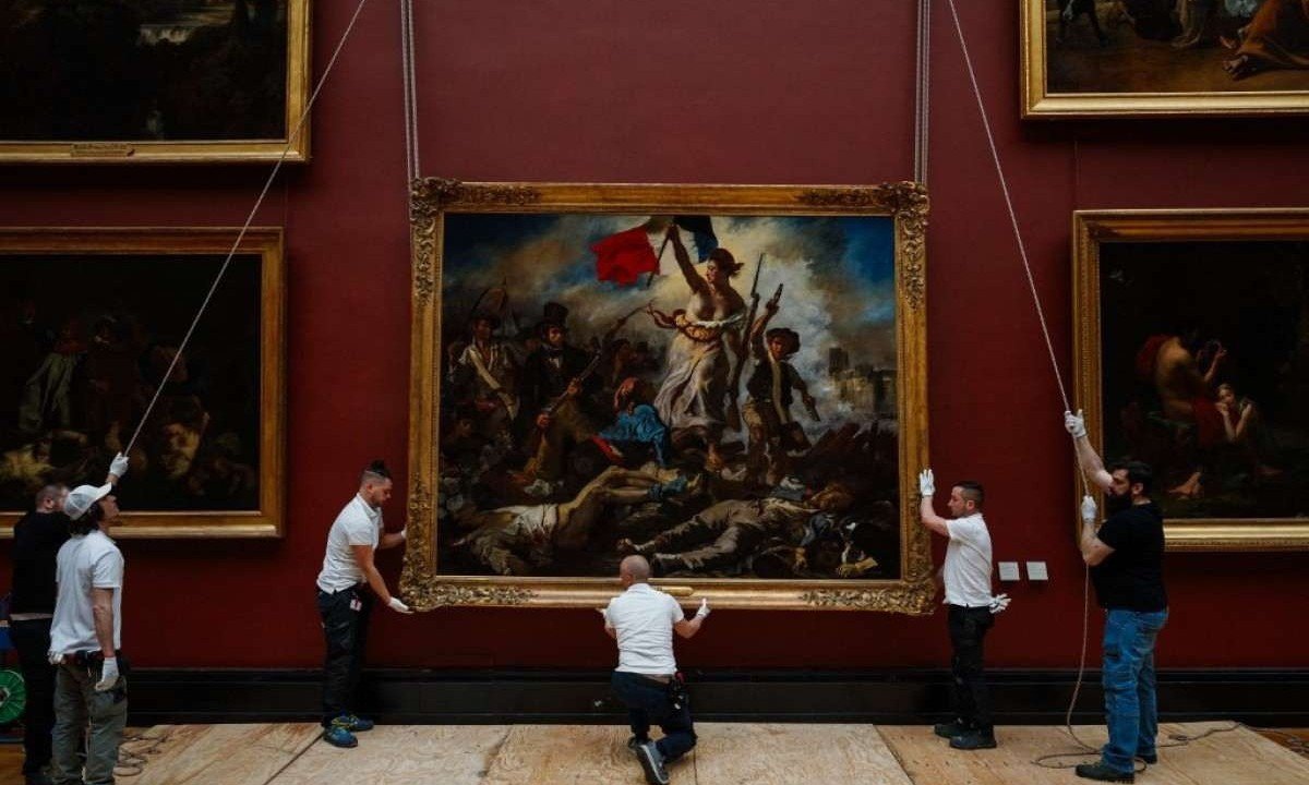 Funcionários do Louvre penduram de volta em galeria do museu quadro de Delacroix restaurado -  (crédito: Dimitar DILKOFF / AFP)