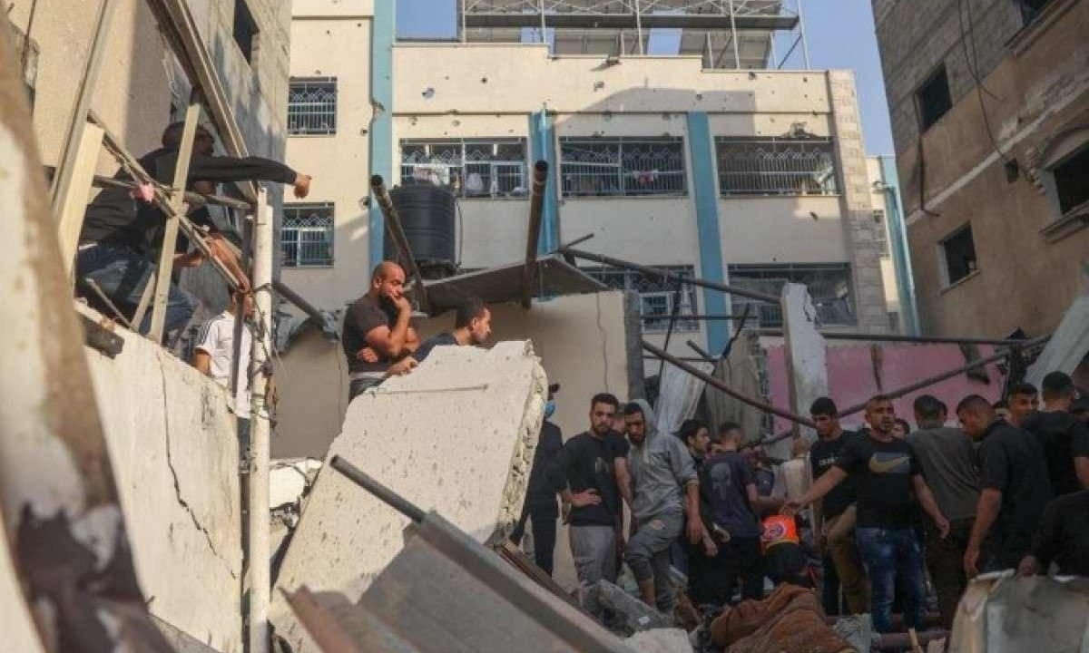 Palestinos buscam por sobreviventes nos escombros de prédio destruido após bombardeio israelense em Rafah, no sul do enclave -  (crédito: AFP)