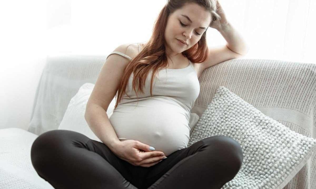 Mulher grávida segura a barriga e joga cabelo para trás, refletindo sobre as consequências com o parto e nascimento do bebê -  (crédito: Freepik)