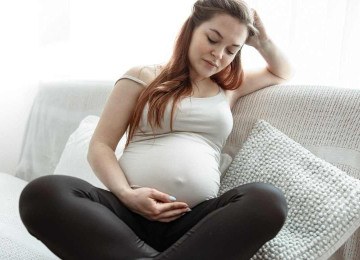 Mulher grávida segura a barriga e joga cabelo para trás, refletindo sobre as consequências com o parto e nascimento do bebê -  (crédito: Freepik)