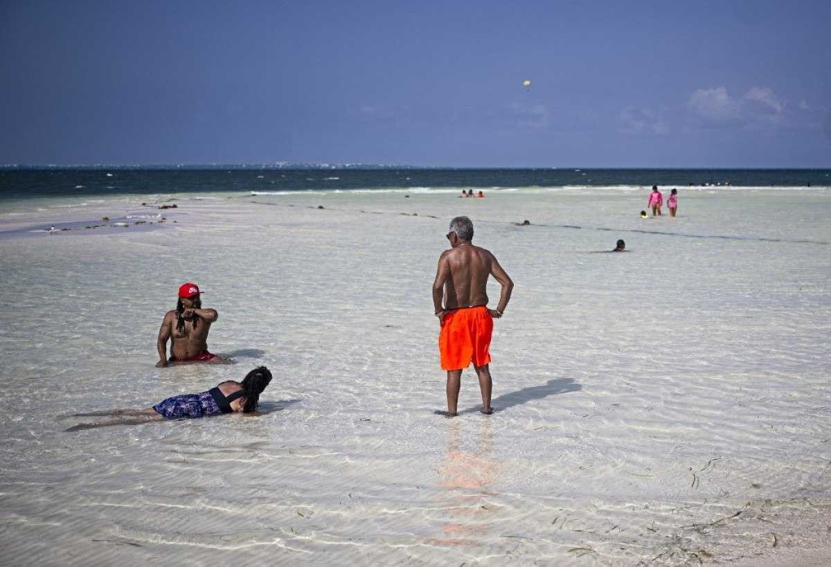Banhistas aproveitam uma praia em Cancún, México, em 23 de abril de 2024. Para muitos moradores de Cancún, seus subúrbios da classe trabalhadora e a zona hoteleira de luxo parecem mundos à parte