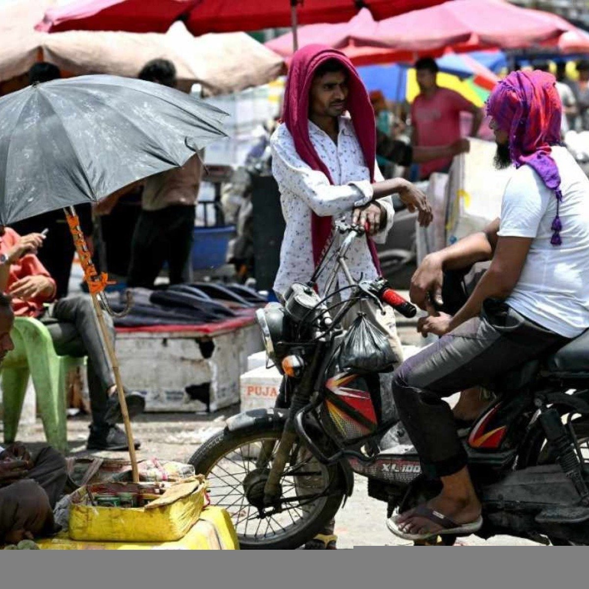 Homens cobrem a cabeça com panos ou guarda-sóis contra tarde de recorde de calor em Nova Delhi
       -  (crédito: Arun SANKAR / AFP)