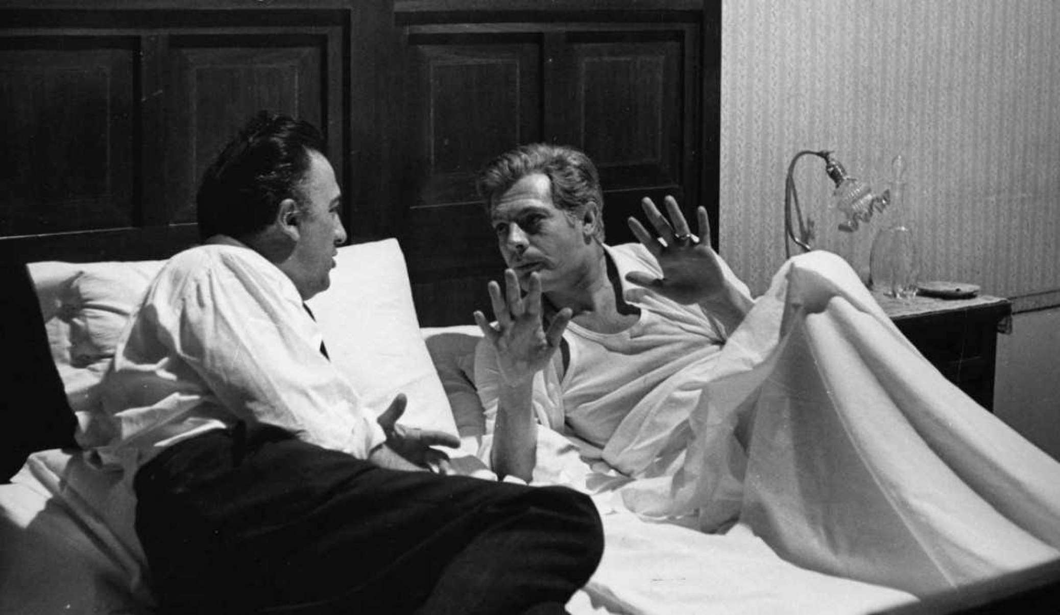 O diretor Federico Fellini e o ator Marcelo Mastroianni, numa cama, durante as filmagens de Oito e meio