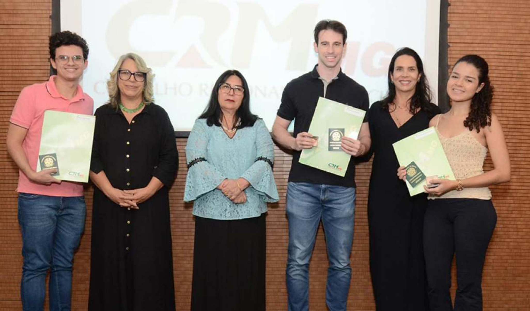 Jovens com professores recebendo a carteira profissional de Médico CRM.