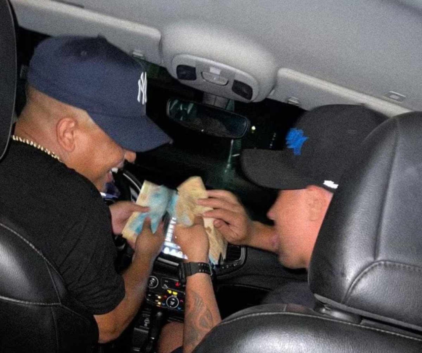 Douglas Emanuel Vilela de Oliveira e outra pessoa dentro de um carro mexendo com dinheiro