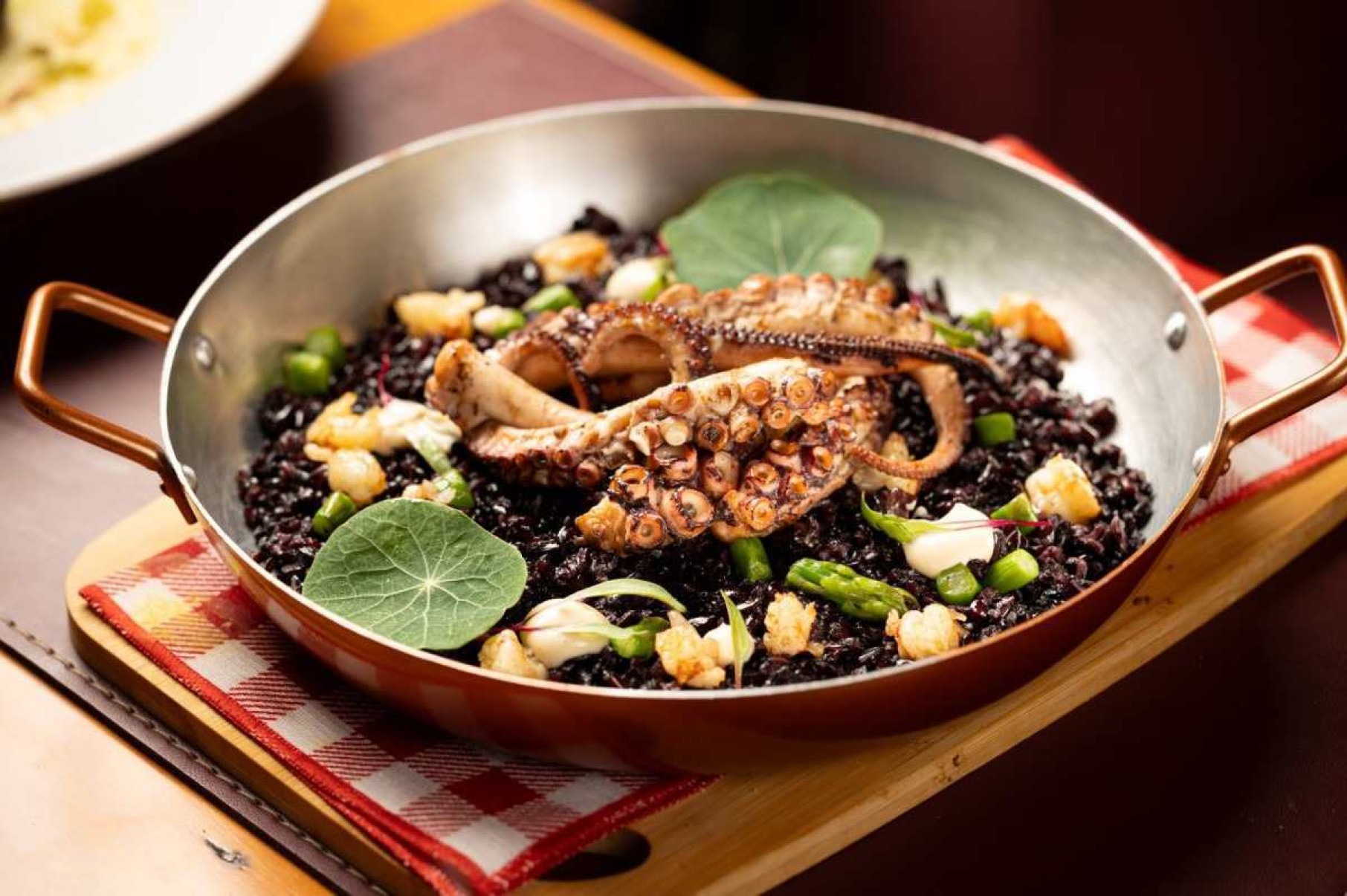Polvo assado na grelha com arroz negro, aspargos, emulsão de endro e camarões é um dos novos pratos do menu de inverno