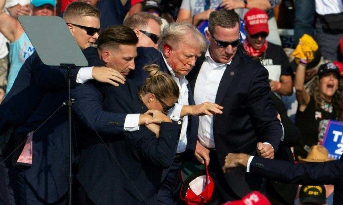 Agentes de segurança amparam Donald Trump, pouco depois de ser atingido por tiro na orelha direita
       -  (crédito:  AFP)